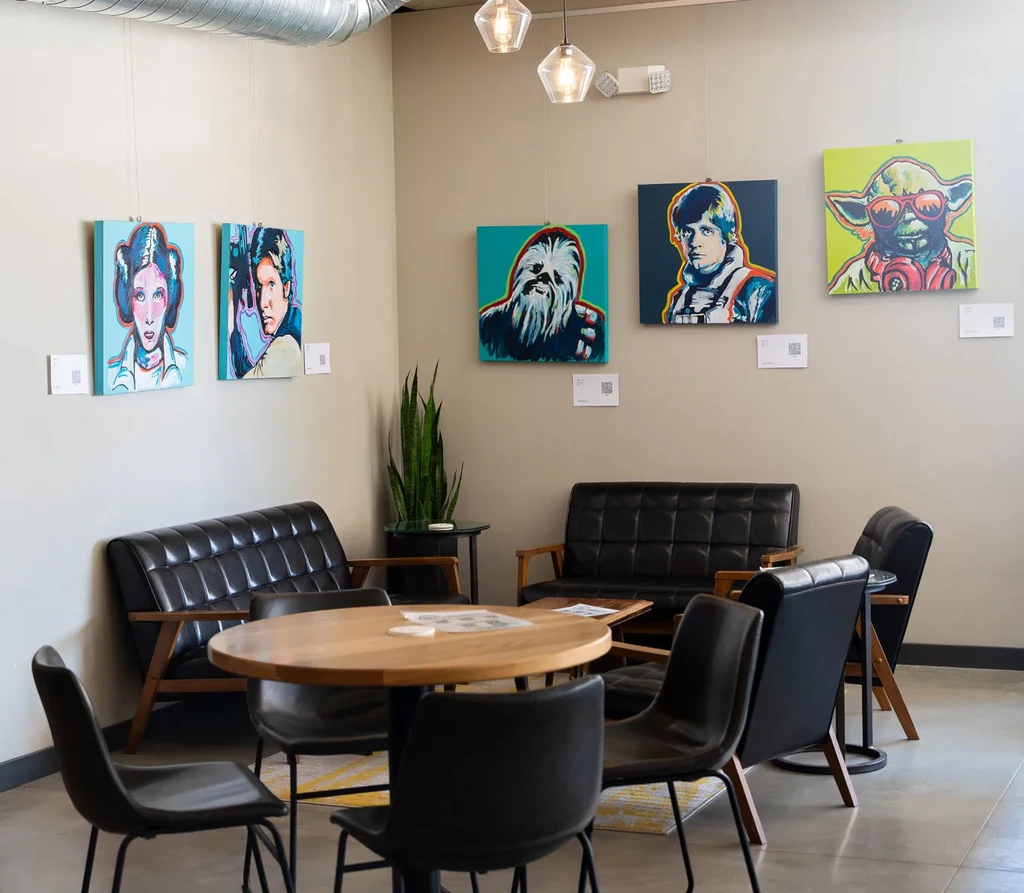 Lounge with black sofas and five Star Wars pop art portraits.