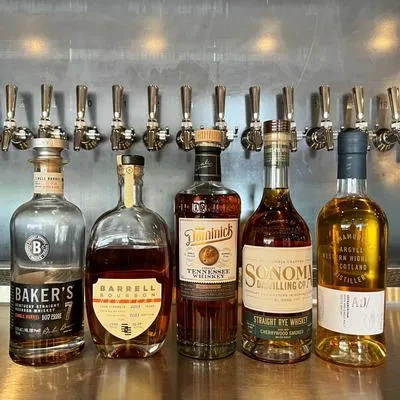 Five unique spirit bottles in front of eight bar taps.