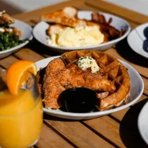 Close-up of chicken and waffles, orange juice, and other brunch dishes.