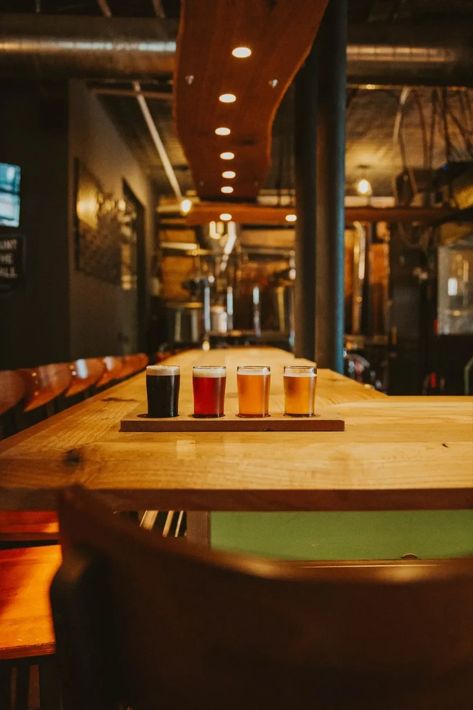 Four different beers on a flight board in a warm brewery.