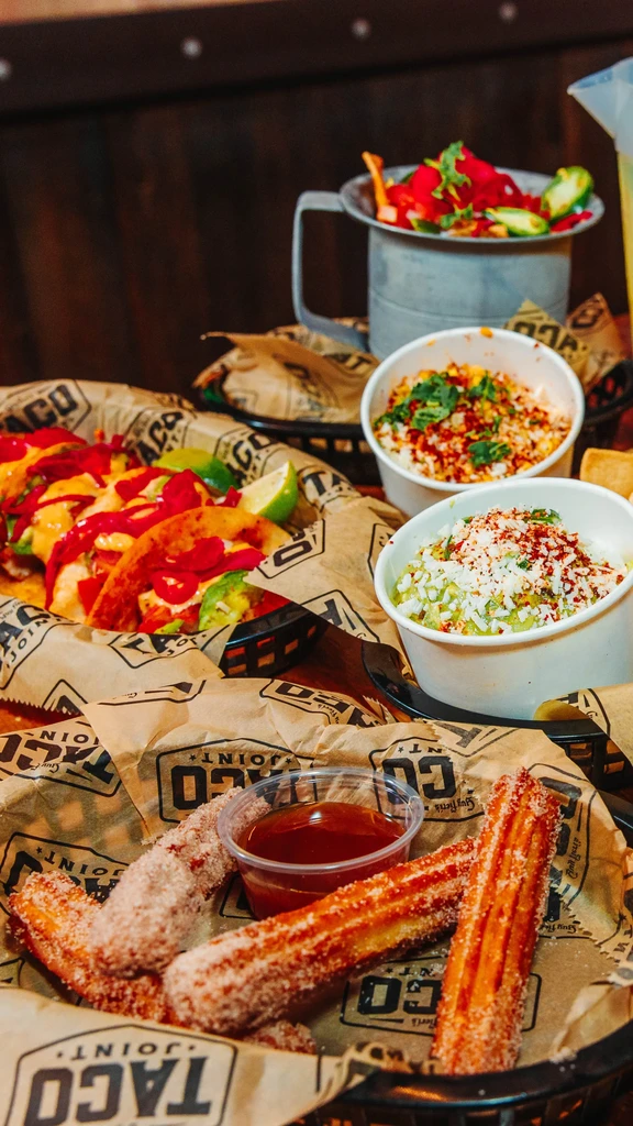 Overhead view of Mexican tacos, churros, guacamole, and esquites.