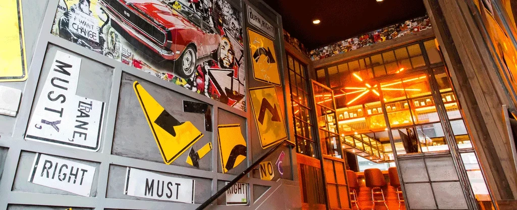 Eclectic urban wall art with road signs and car poster in a bar.