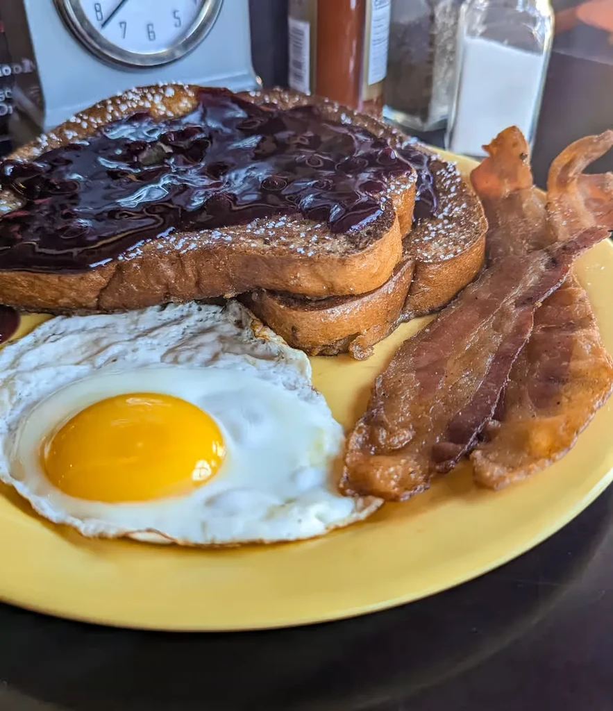 French toast with compote, crispy bacon, and a sunny-side-up egg.