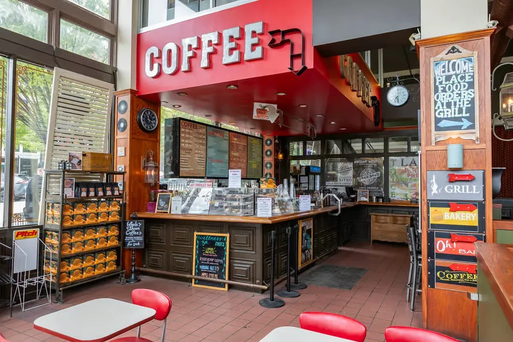 Restaurant interior with coffee counter, red "COFFEE" sign, and seating.
