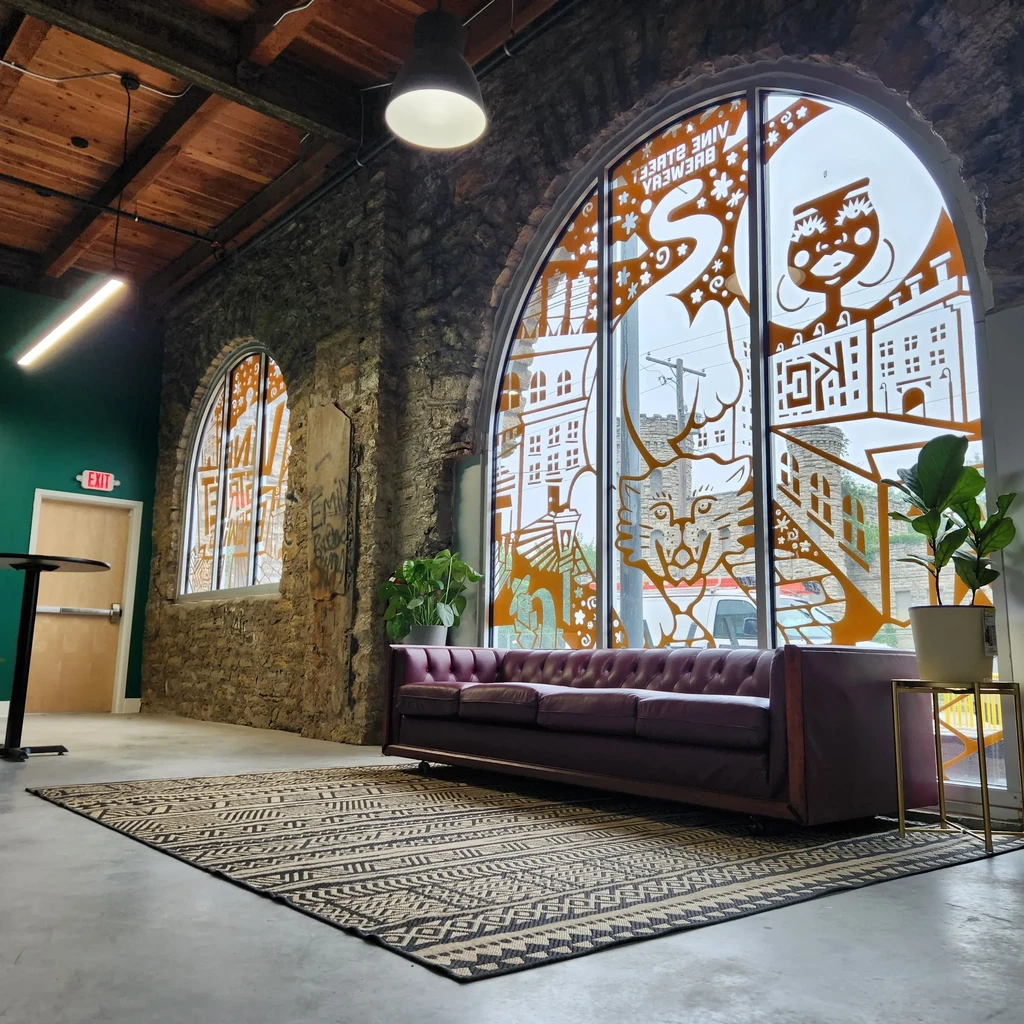 Brewery lounge interior with arched windows, exposed beams, and a purple sofa.
