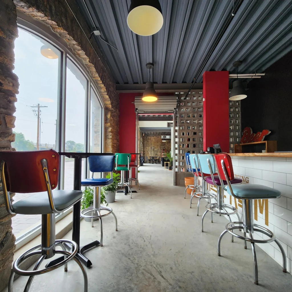 Modern industrial bar, retro stools, exposed brick, corrugated ceiling.
