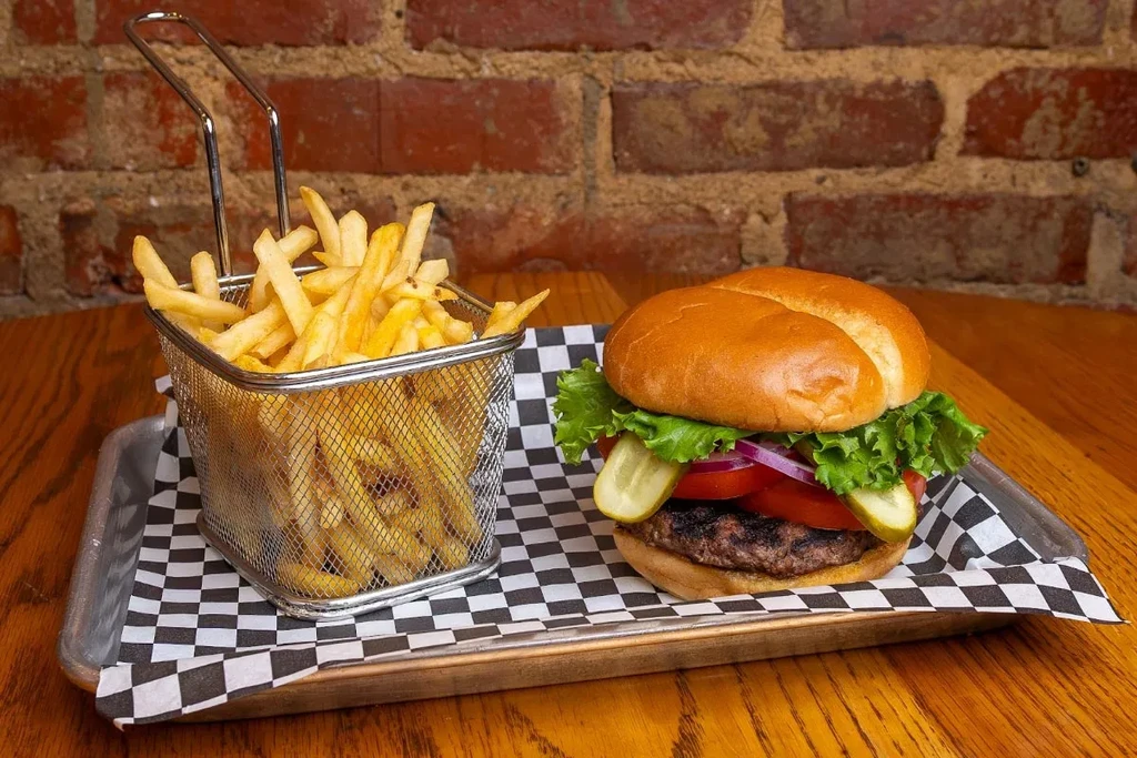 A grilled hamburger and crispy fries on a checkered tray.