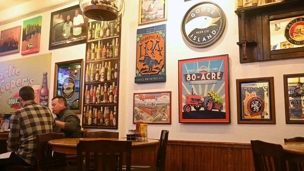 Bar wall heavily adorned with numerous framed beer signs and artwork.