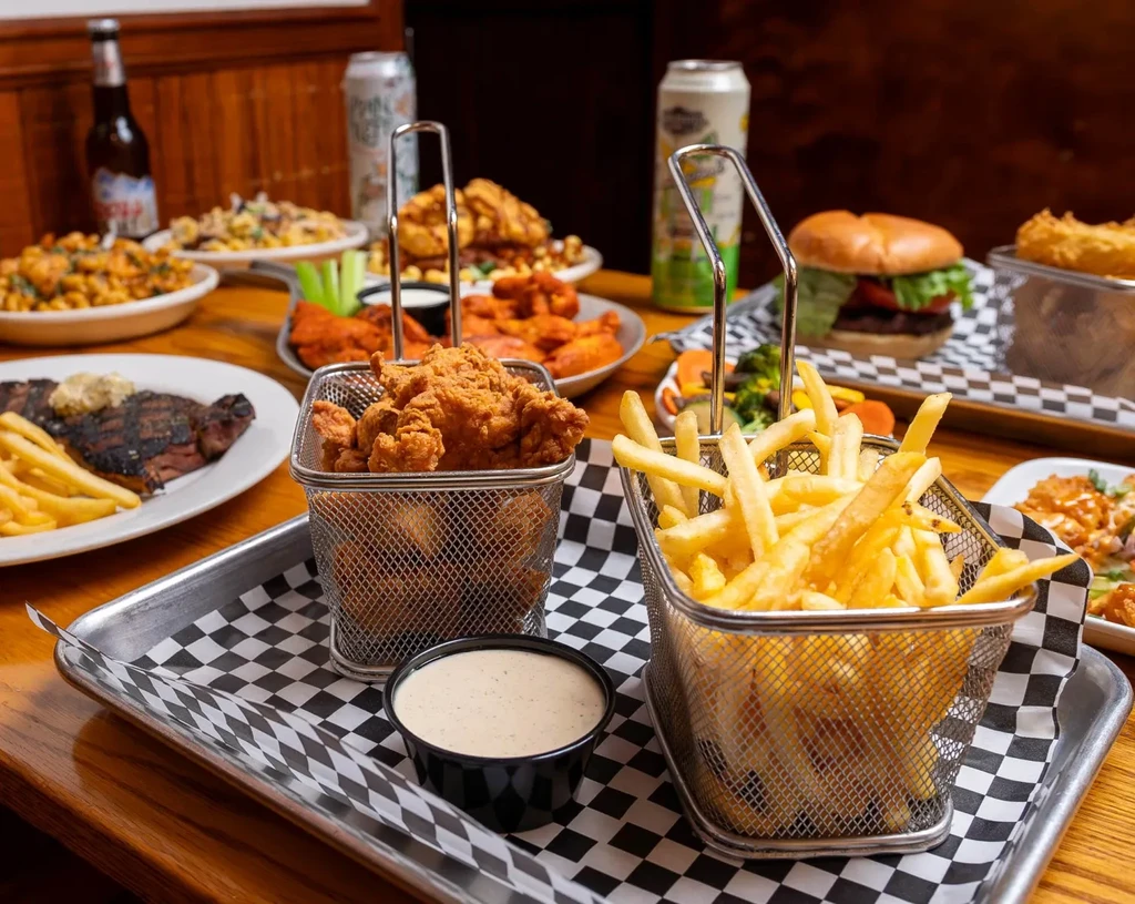 Close-up of fried chicken and fries; a table full of food.