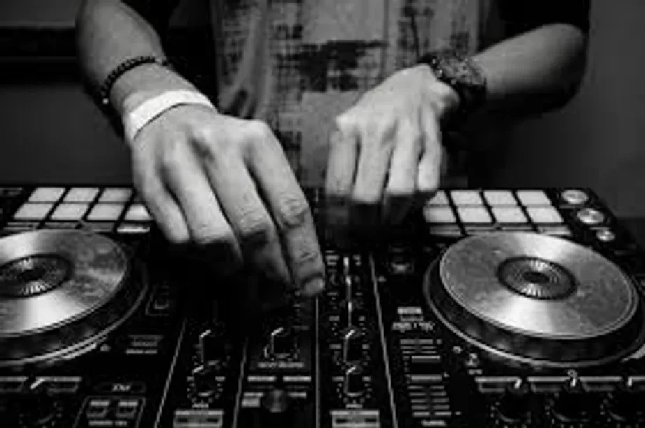 Black and white image of hands operating DJ equipment.