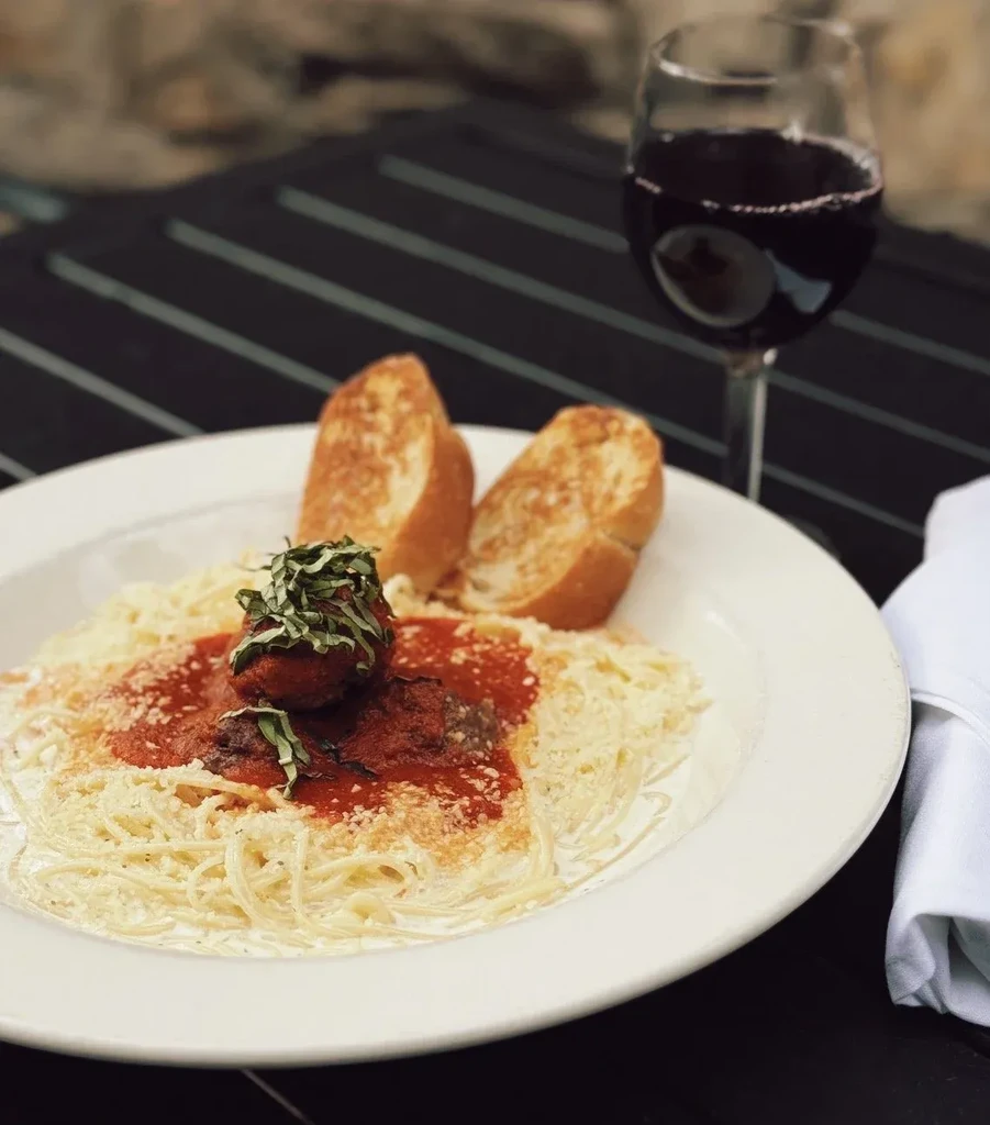 Spaghetti with meatballs, garlic bread, and red wine.