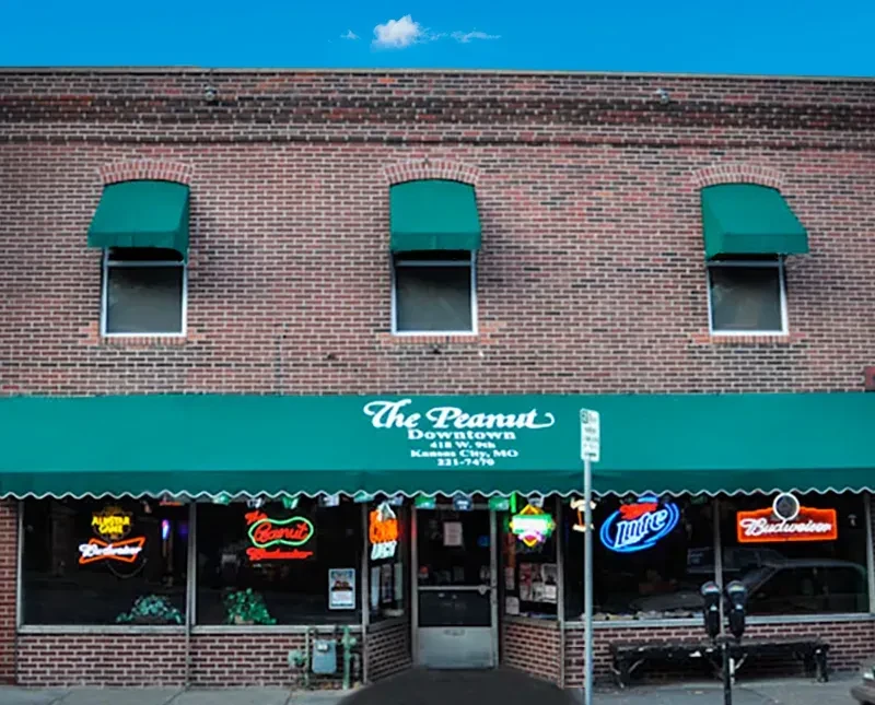 "The Peanut Downtown" brick building with green awnings and neon signs.