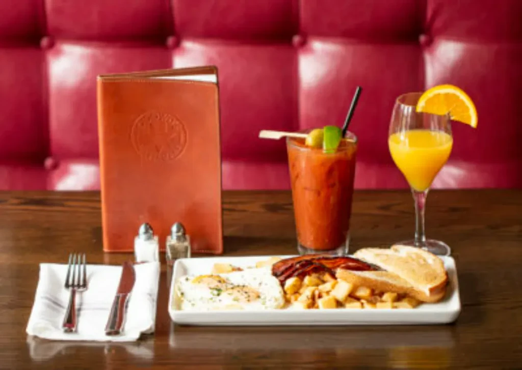 Breakfast plate, Bloody Mary, and orange juice on a dark table.