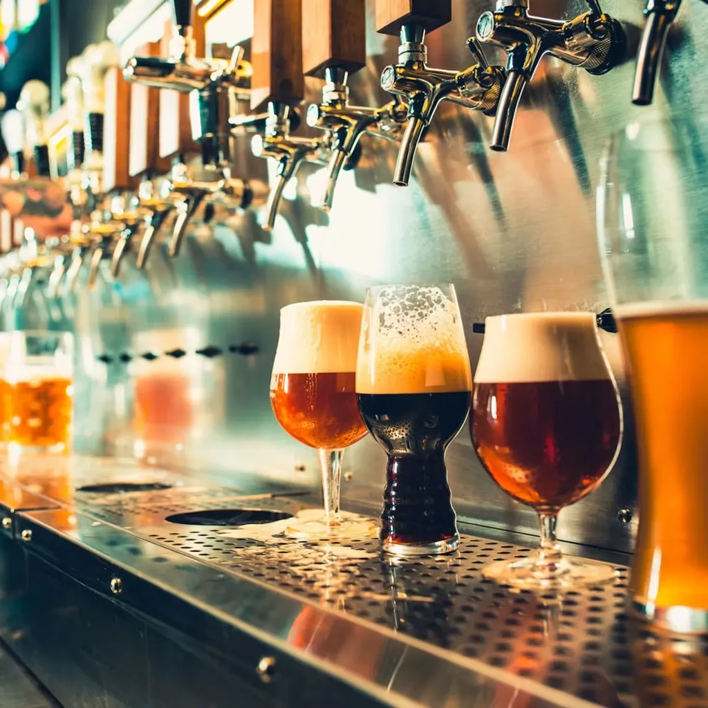 Four varied craft beers on a bar counter with shining taps.