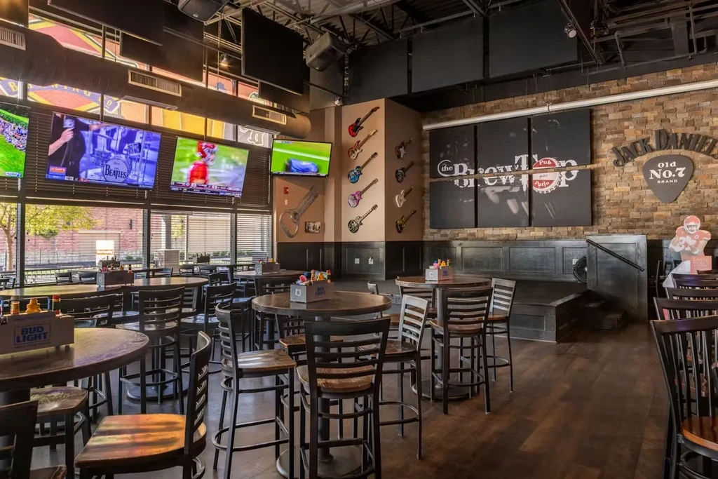 Casual pub interior with TVs, electric guitars, and an empty stage.