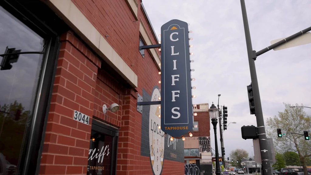Cliffs Taphouse exterior: prominent vertical sign, circular mural, red brick.