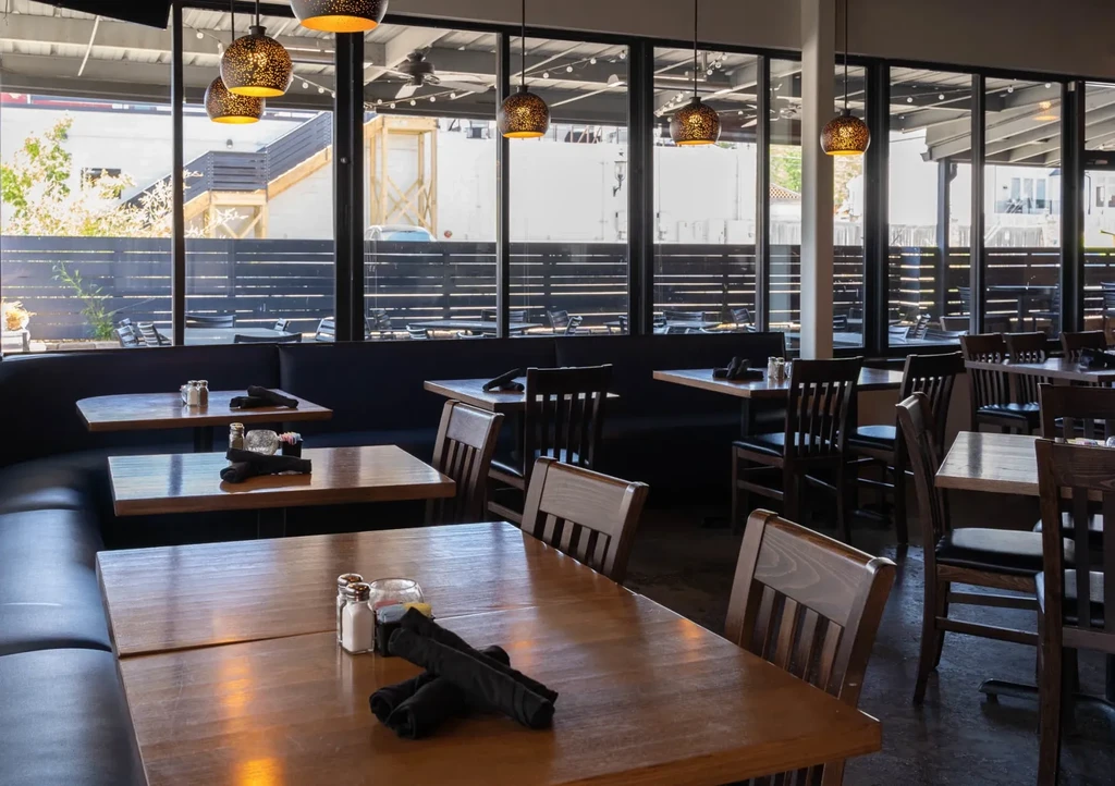 Empty modern restaurant dining room with set tables and patio view.