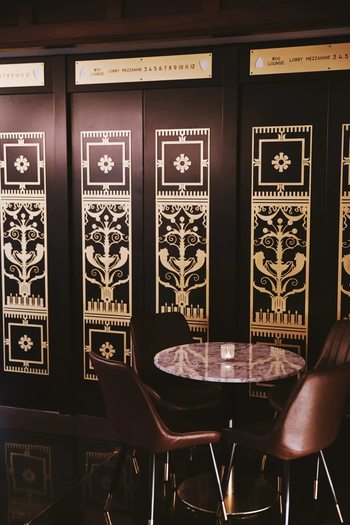 VDO LOUNGE with marble table, candle, chairs, and gold Art Deco patterns.