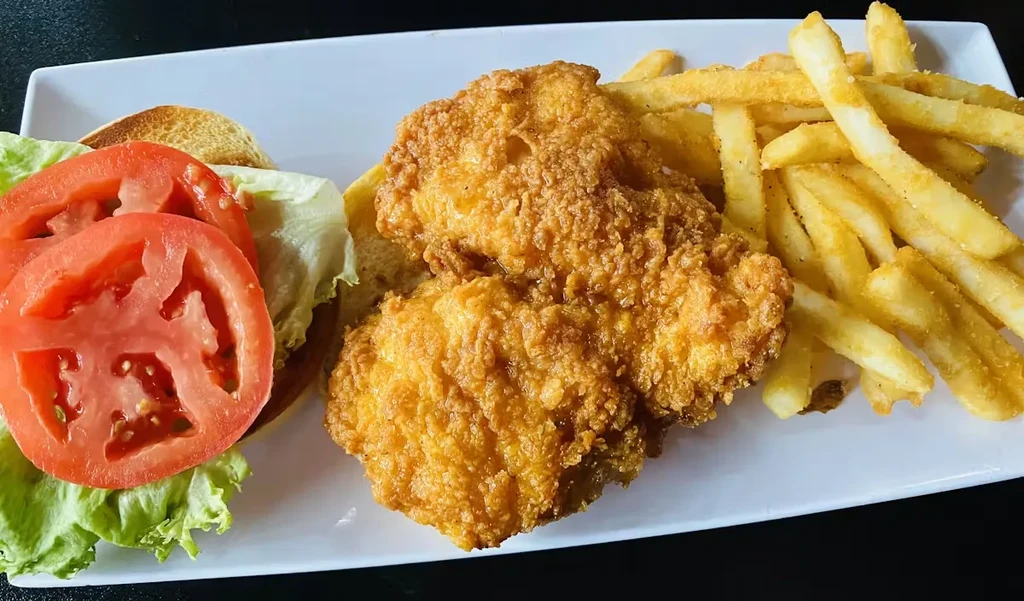 Top-down view of a deconstructed fried chicken sandwich and french fries.