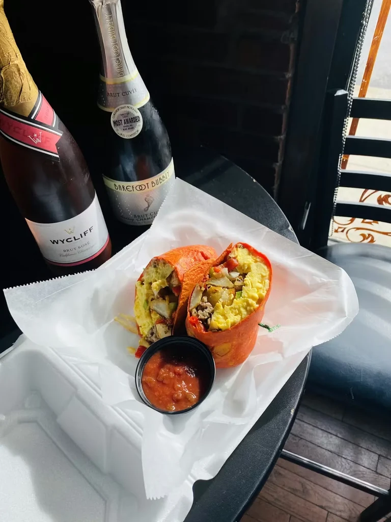 Cut breakfast burrito, salsa, and two sparkling wine bottles.