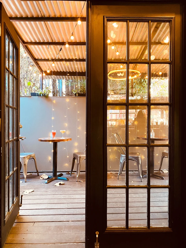 Warm evening patio with string lights, tables, and two cocktails.
