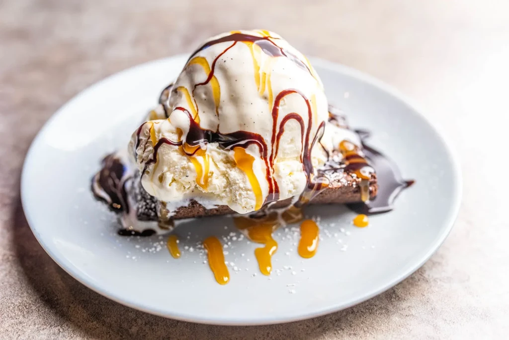 Brownie topped with melting vanilla ice cream, chocolate, and caramel sauce.