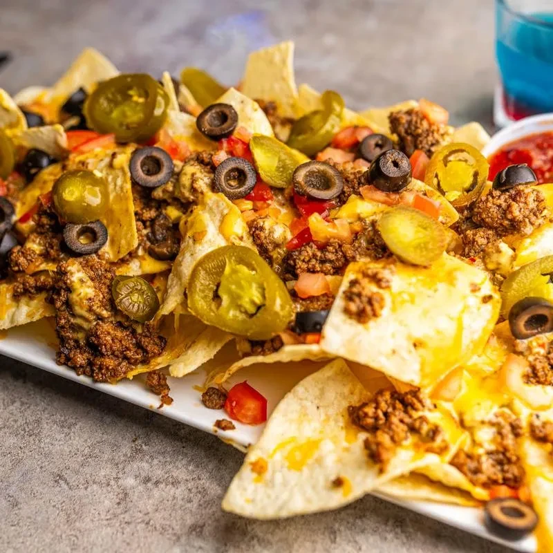 Large nachos with melted cheese, ground meat, olives, tomatoes, and jalapeños.