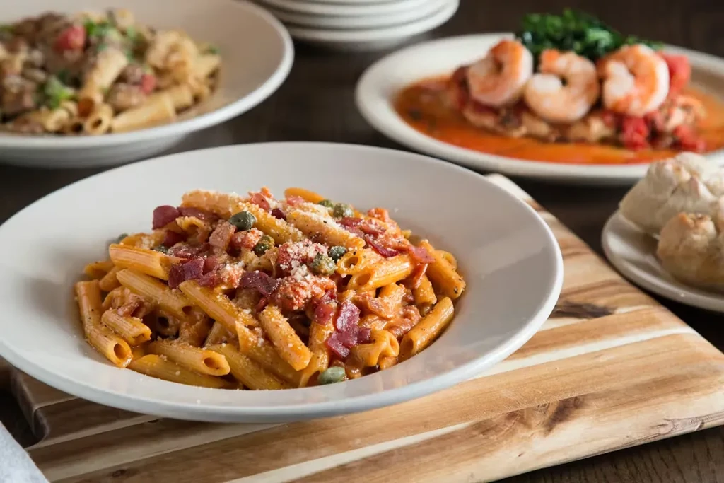Penne pasta with red sauce, bacon, capers, and cheese.