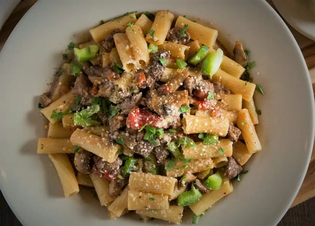 Pasta with meat, tomatoes, green peppers, cheese, and fresh herbs.