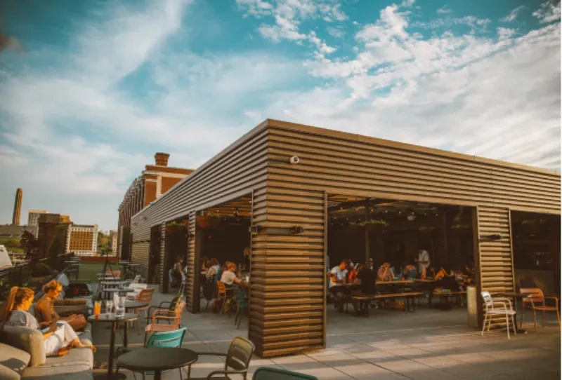 Rooftop restaurant with outdoor lounge, indoor dining, and urban skyline.