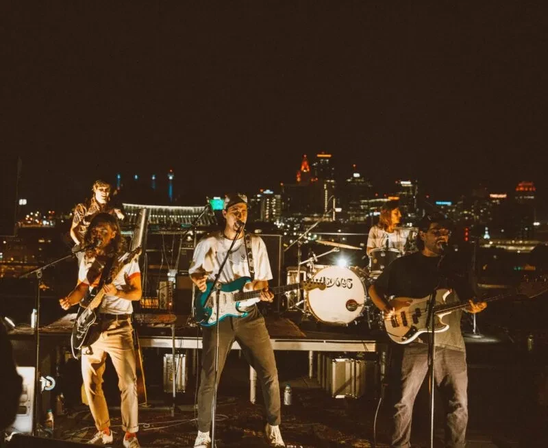 WILD DOGS band performs live outdoors at night with city skyline.