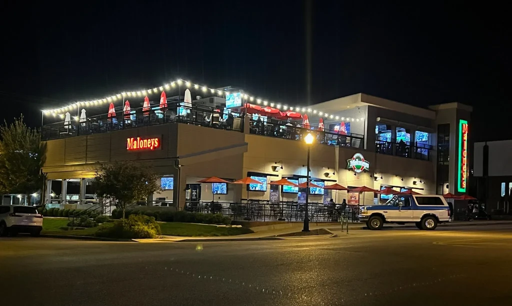 Maloneys two-story restaurant at night with illuminated patios and Bronco.