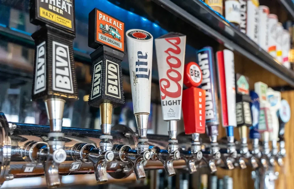 Close-up of multiple branded beer taps at a dim bar.