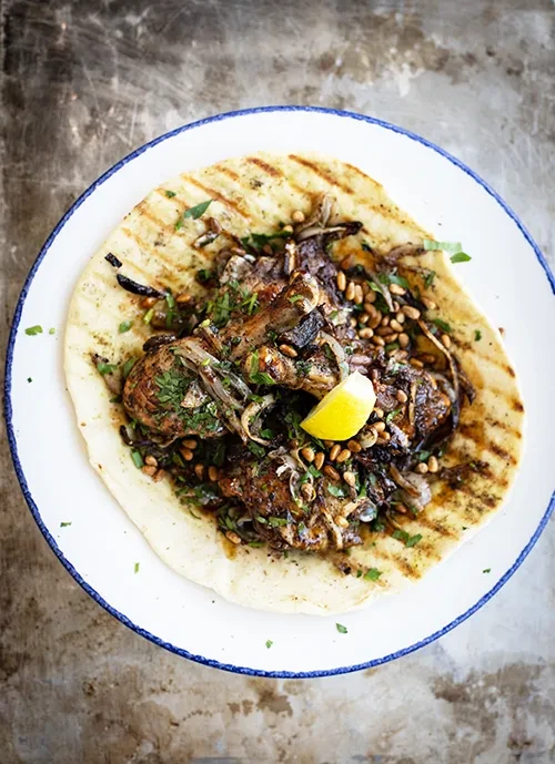 Rustic grilled meat, onions, herbs, pine nuts, lemon on flatbread.