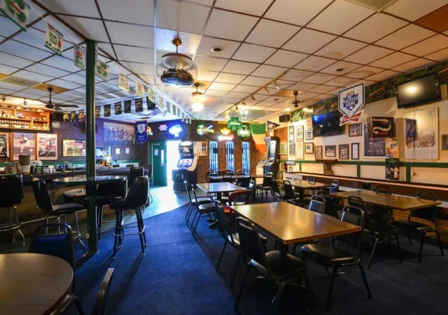Empty casual bar with prominent bar counter, tables, and wall decor.
