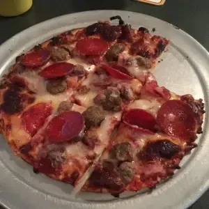 Hot pepperoni and sausage pizza on a pan with one slice removed.