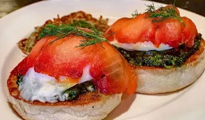 Two servings of smoked salmon Eggs Benedict with poached eggs and dill.