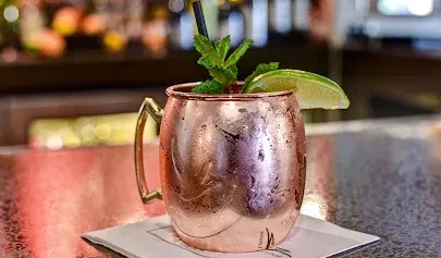Iced beverage in a frosty copper mug with lime and mint.