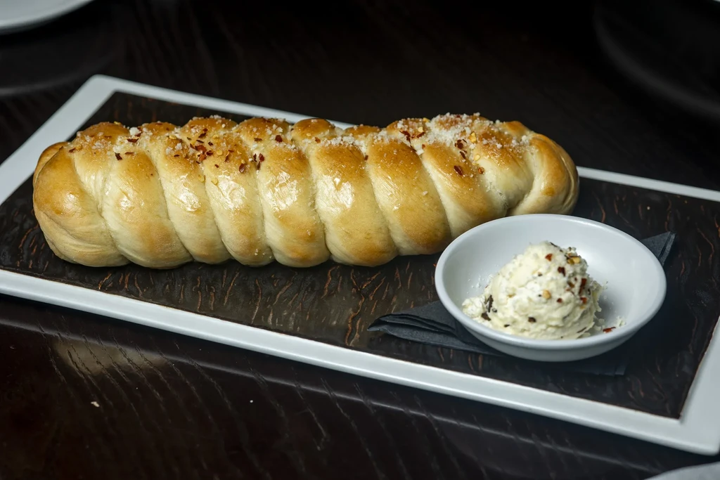 Braided golden bread with salt, red pepper flakes, and creamy dip.