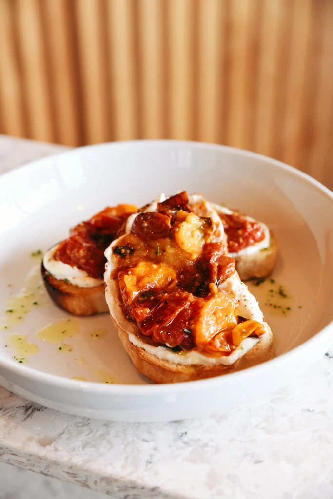 Toasted bread topped with vibrant roasted tomatoes, herbs, and olive oil.