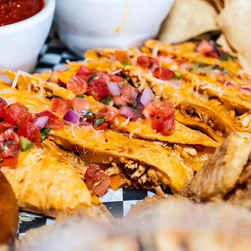 Golden-brown mini tacos with shredded meat, melted cheese, and pico.