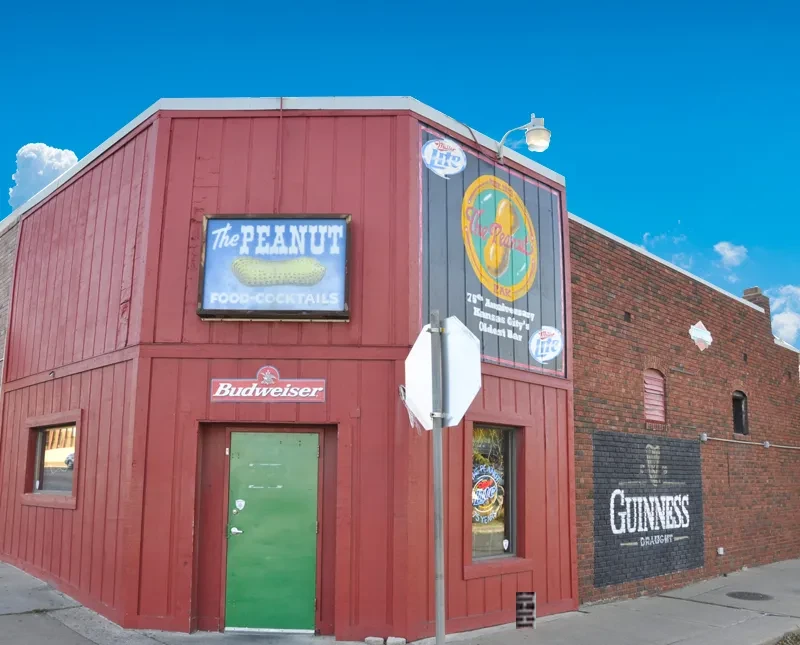 Red two-story "The Peanut" bar building, next to brick building.