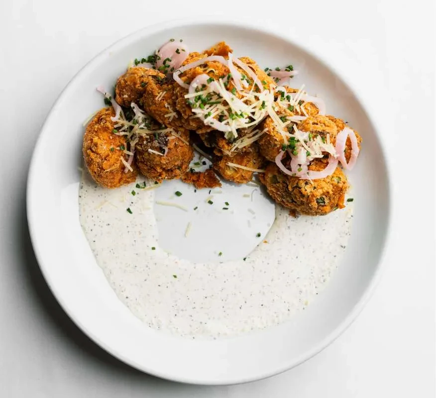 Crispy fried fritters with cheese, pickled onions, herbs, and white dipping sauce.