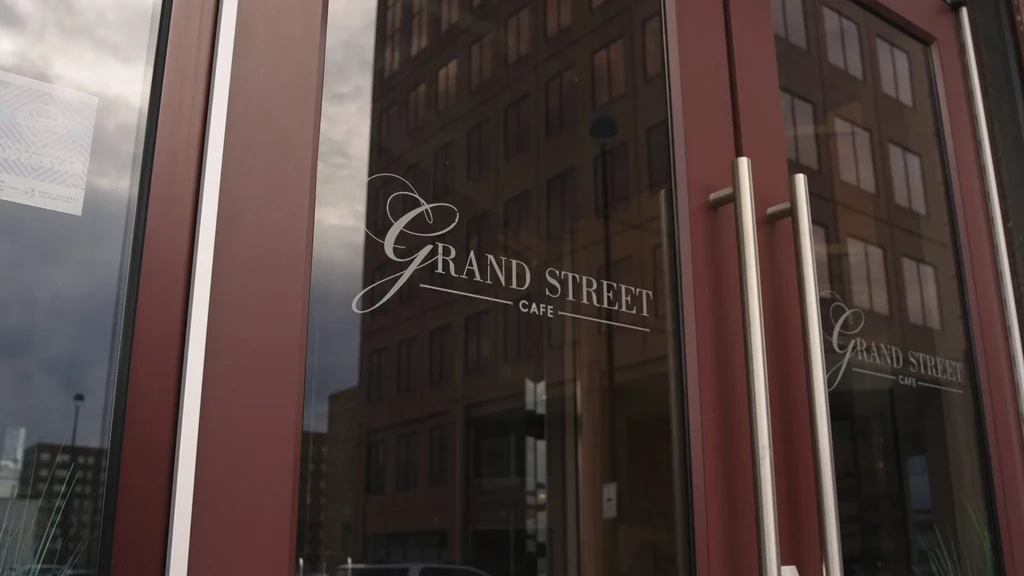 Reddish-brown framed glass double doors of Grand Street Cafe.