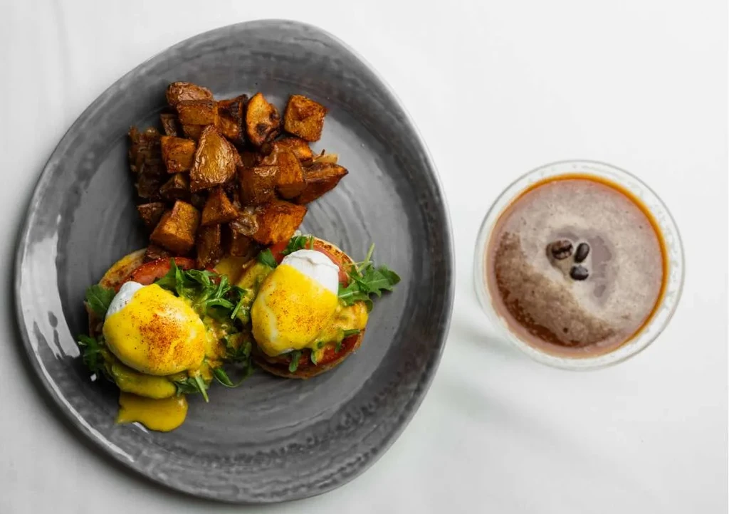 Overhead view: Eggs Benedict, roasted potatoes, and coffee.