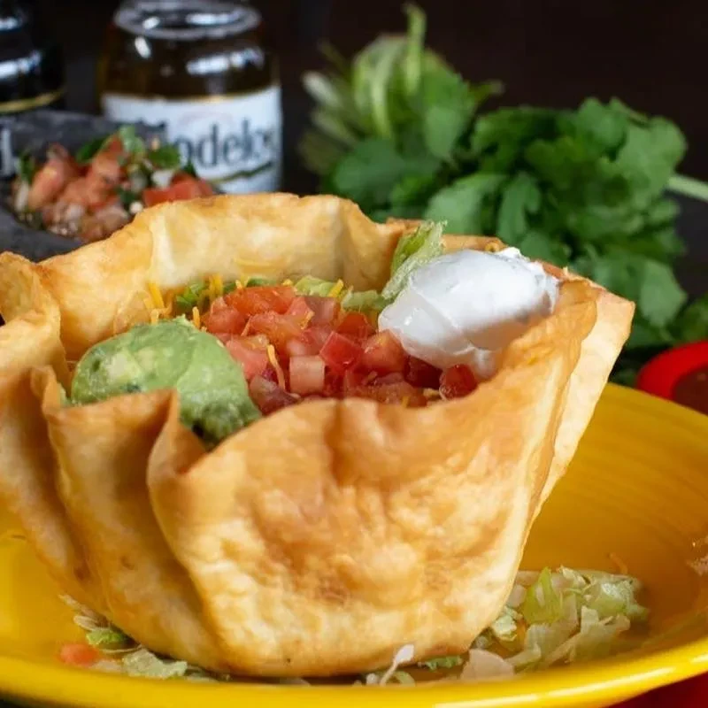 Taco salad in a crispy tortilla bowl with guacamole and sour cream.