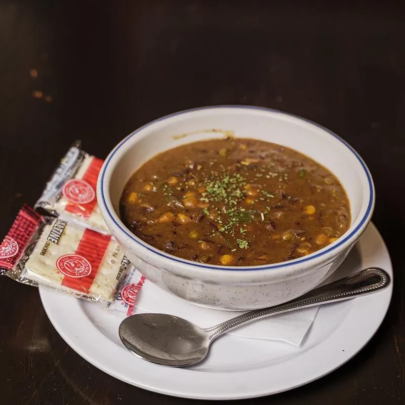 Dark, chunky soup with corn, green herbs, and Saltine crackers.