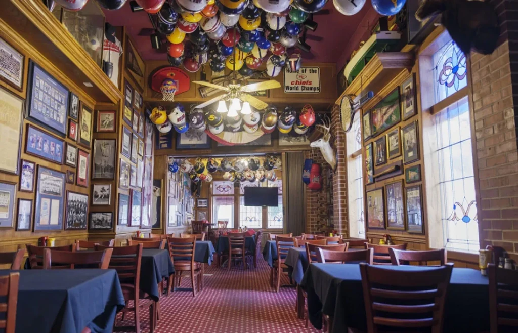 Densely decorated sports bar with hanging helmets and sports memorabilia.