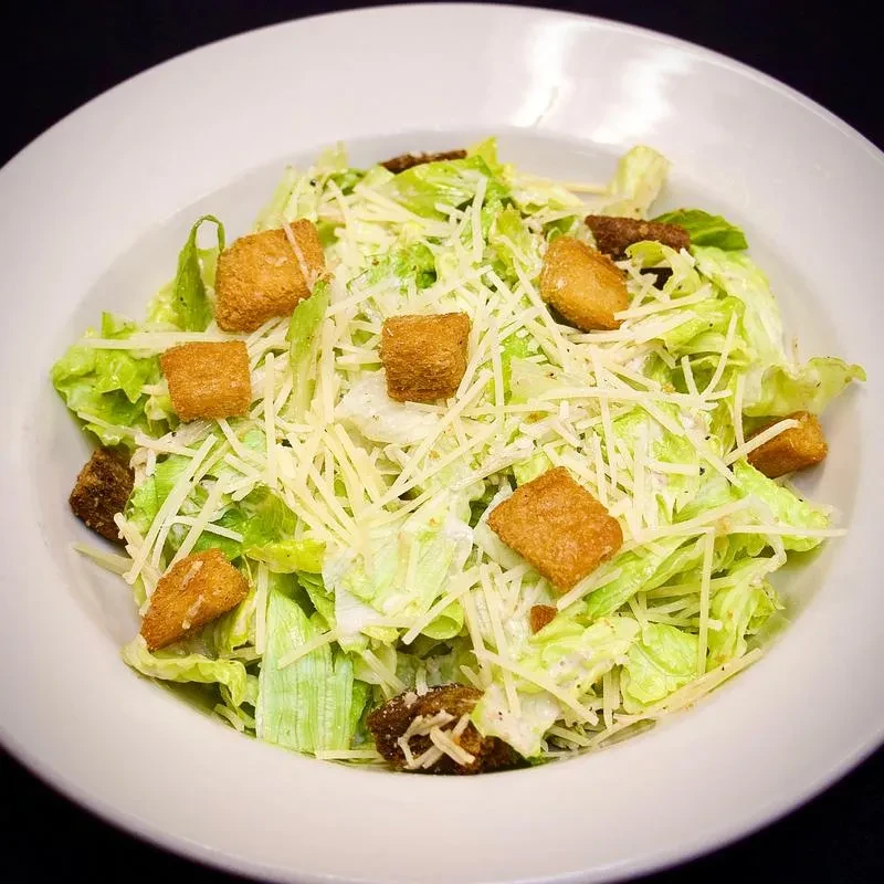 Caesar salad with romaine lettuce, Parmesan cheese, croutons, and dressing.