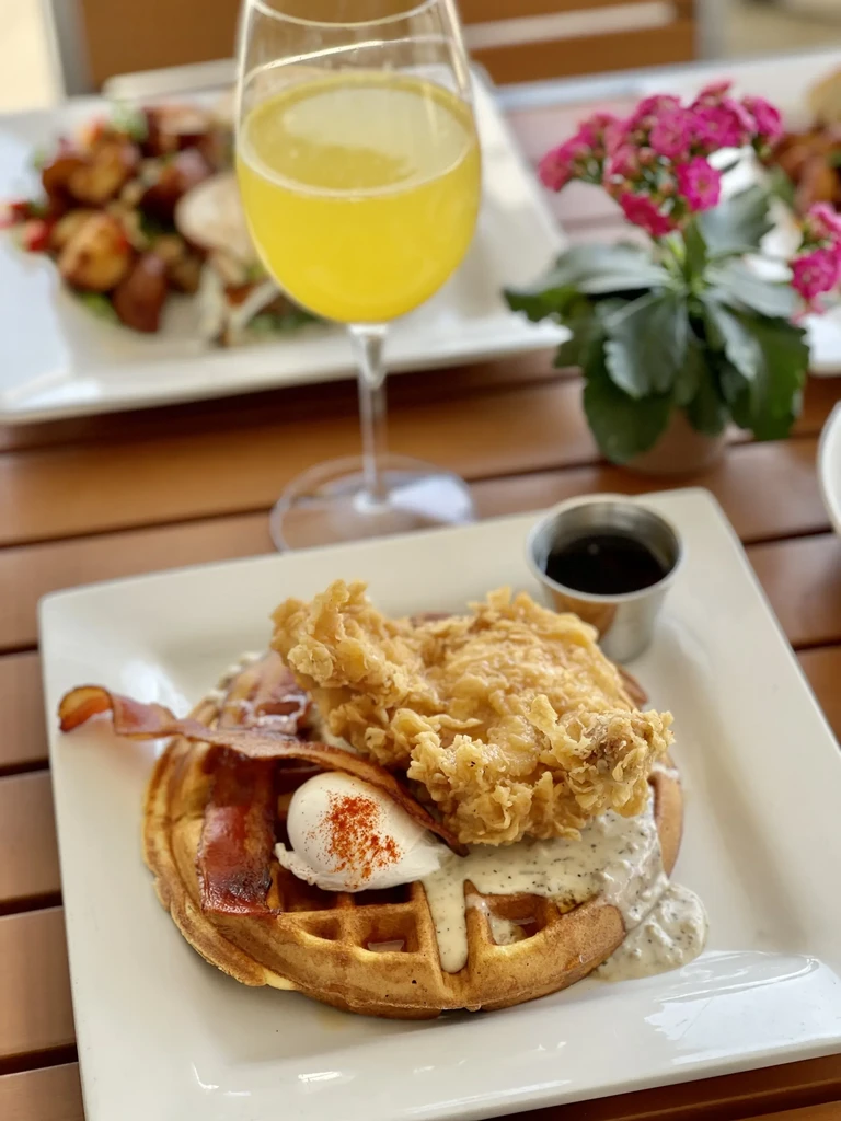 Chicken and waffles with poached egg, bacon, and gravy.